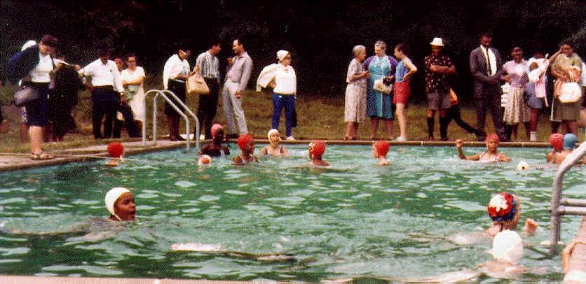 Parents watch their daughters swim on visiting day, July 1965